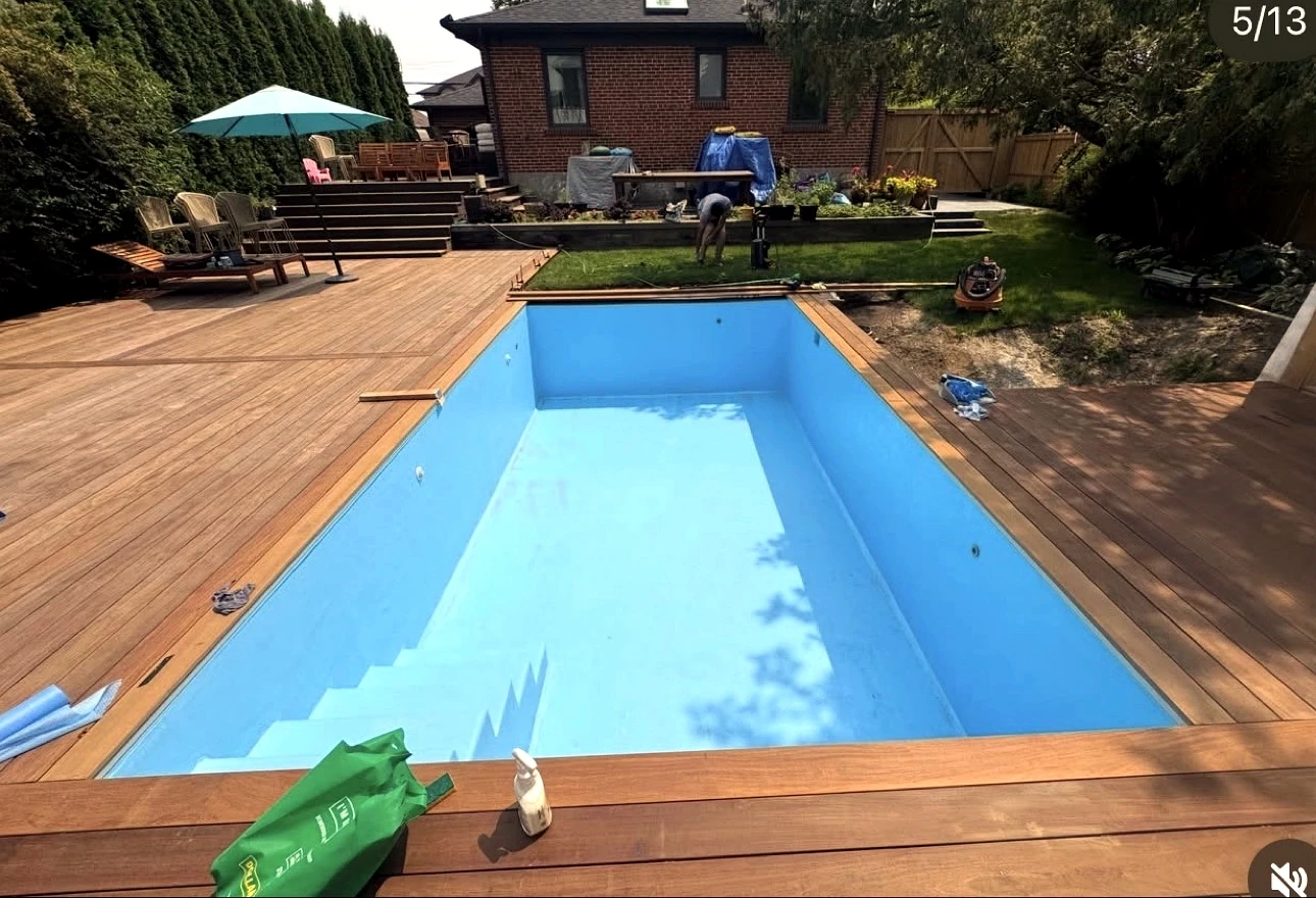 Real Pisces jobsite in summer: pool, wood deck, lawn and a crew member still on site