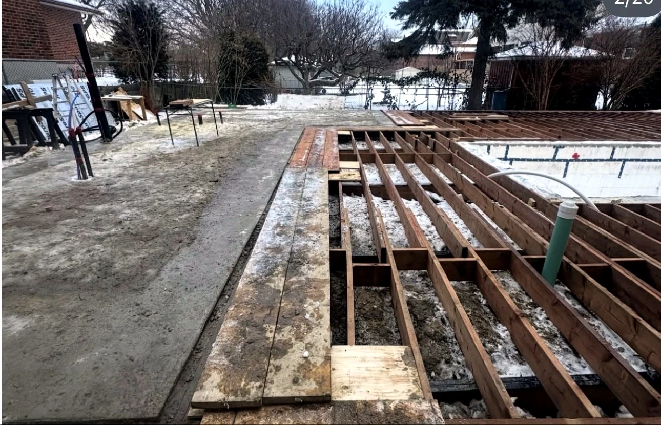 Real Pisces jobsite in winter: deck framing detail with the pool shell under construction