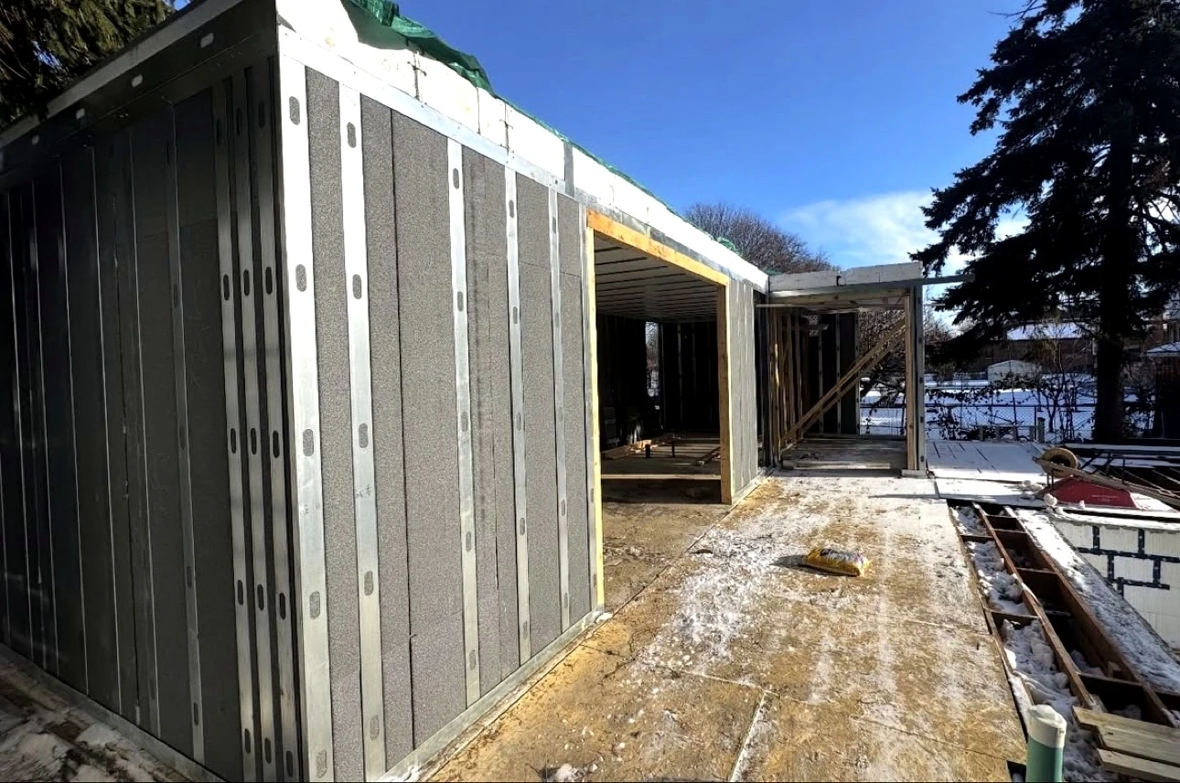 Real Pisces jobsite in winter: steel-frame garden suite structure going up in winter sun