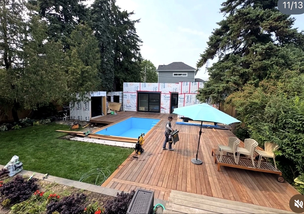 Real Pisces jobsite in summer: blue pool with wood deck, lawn and the weather-wrapped garden suite