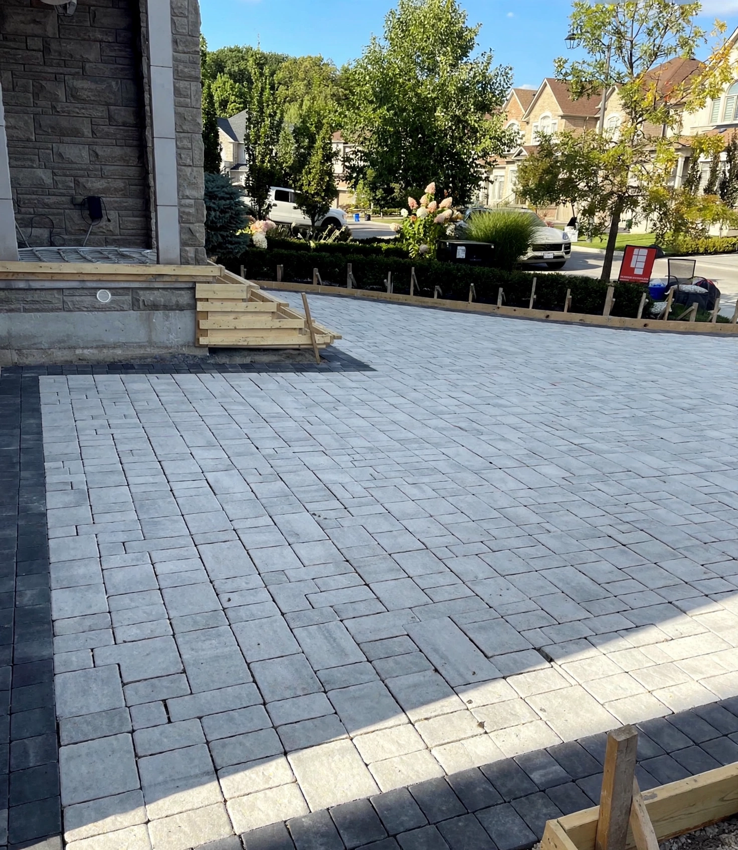 Design concept — finished heated driveway visualization with light-grey interlock pavers and charcoal border accents