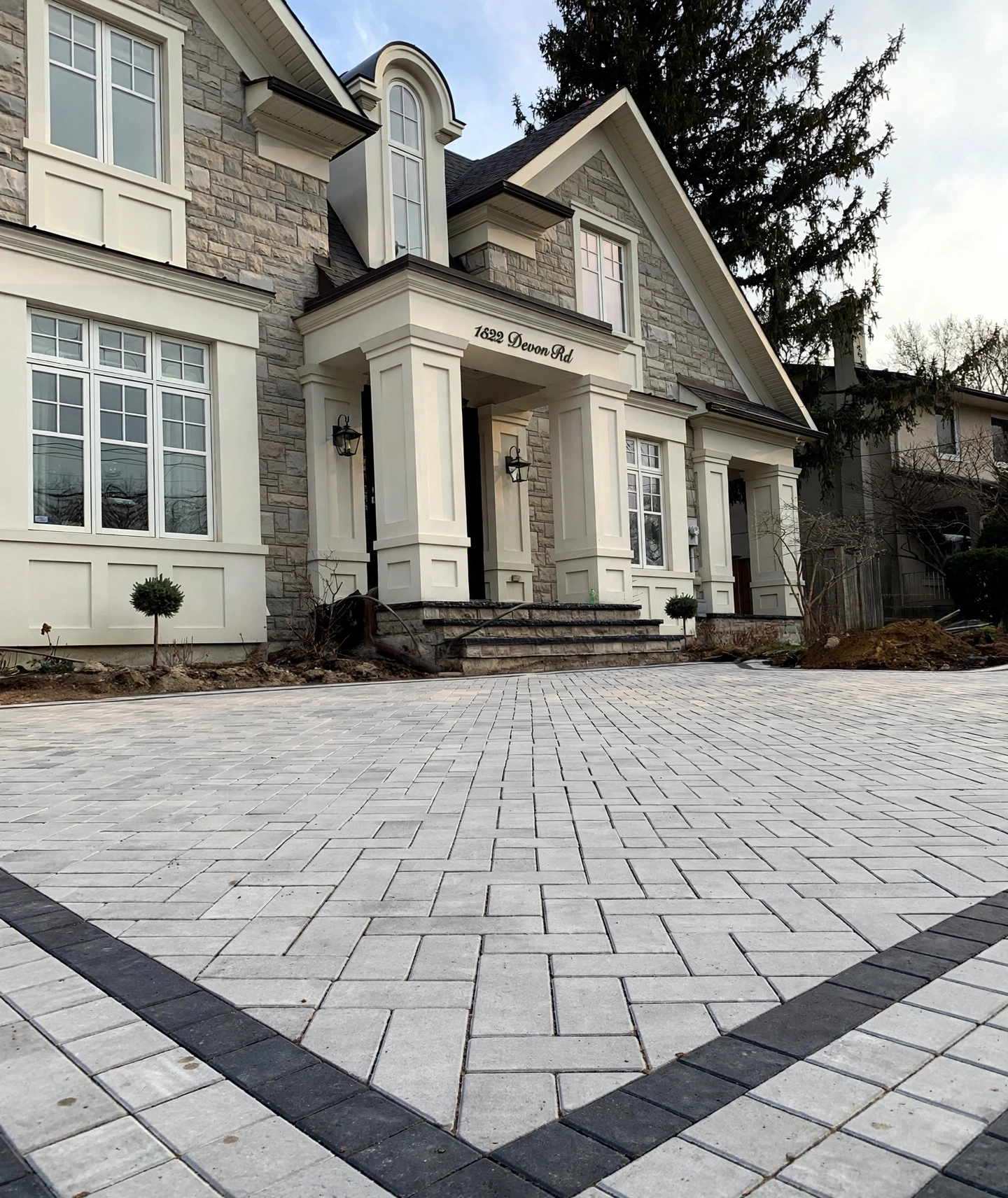 Design concept — finished heated driveway visualization with light-grey interlock pavers and charcoal border accents