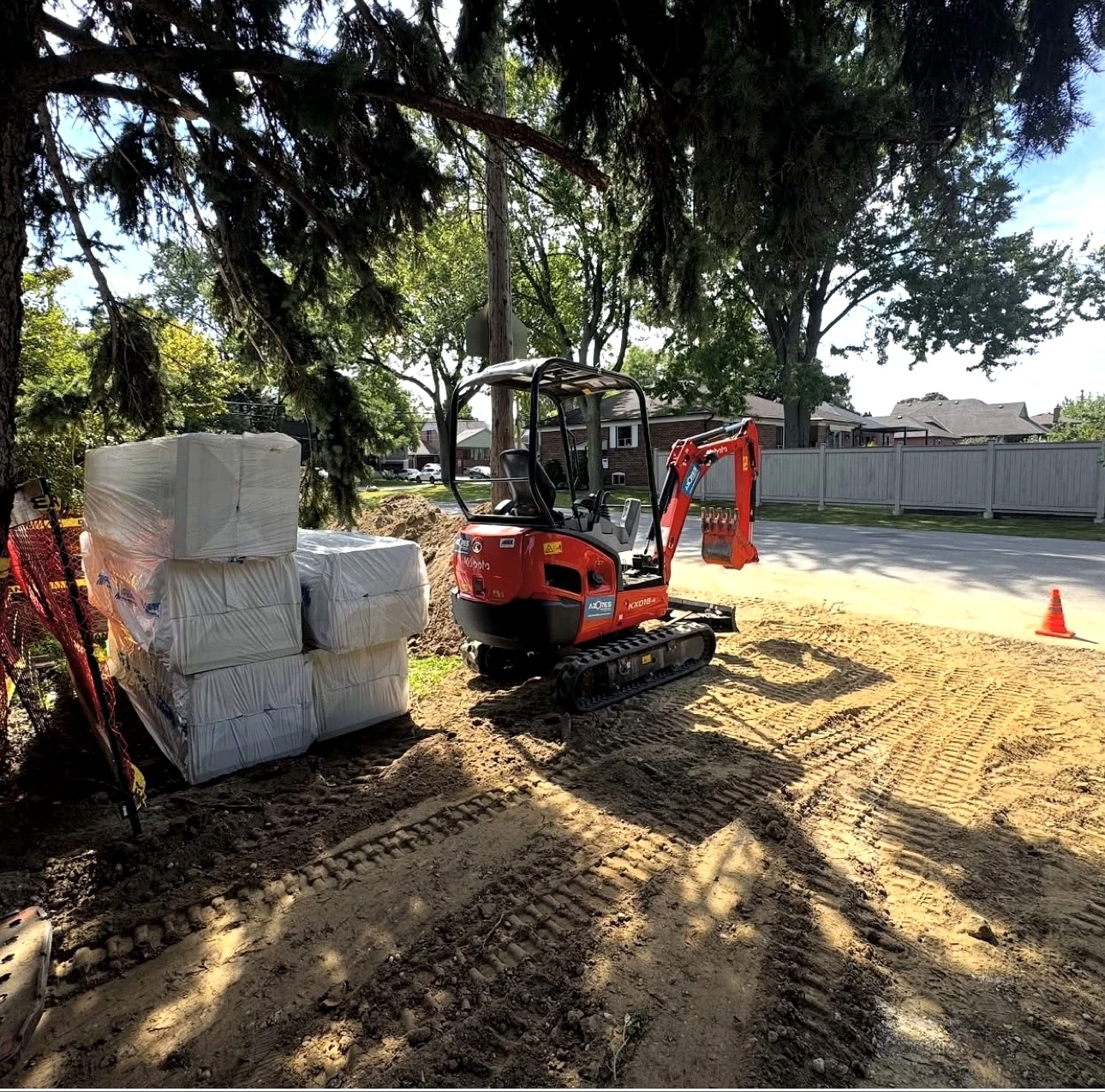 Real Pisces jobsite: Kubota KX018 mini excavator beside wrapped rigid insulation bundles