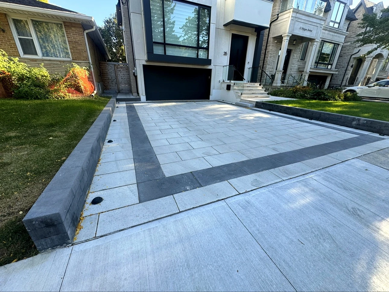 Close-up of interlock driveway charcoal border, retaining wall and lawn edging, Toronto — completed Pisces project